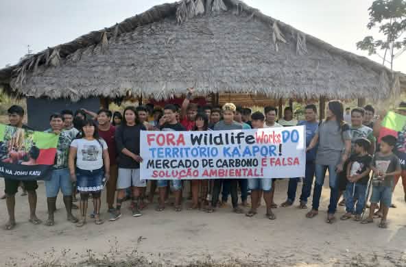 30 indigènes manifestent devant une hutte : « Wildlife Works, sortez du territoire des Ka’apor. Le commerce du carbone n’est pas une solution environnementale viable »